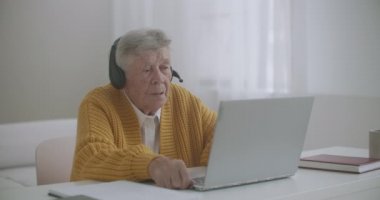 Yaşlı kadın bilgisayarını, kapalı mekanda el hareketlerini gösteren hareketlerle ilgili video konuşması yapmak için kullanıyor. Yaşlı kadın ve modern cihazlar kavramı.