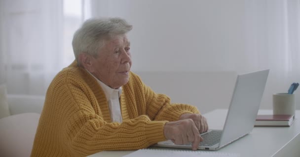 上了年纪的妇女正在用笔记本电脑制作视频通话手势，在室内展示大拇指向上的手势。老年妇女与现代装置概念. — 图库视频影像