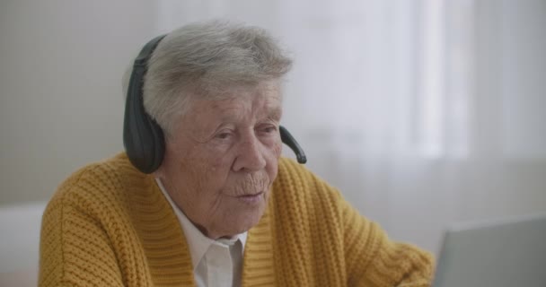 Femme âgée utilisent un ordinateur portable pour faire appel vidéo parler gestuelle montrant pouce vers le haut geste de la main à l'intérieur. Vieille femme et dispositif moderne concept. — Video