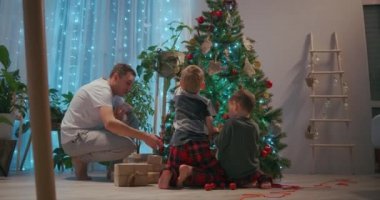 İki çocuklu bir aile Noel arifesinde bir Noel ağacı süsler. Çocuklu anne ve baba yeni yıla ve Noel dekorasyon evine hazırlanıyor.