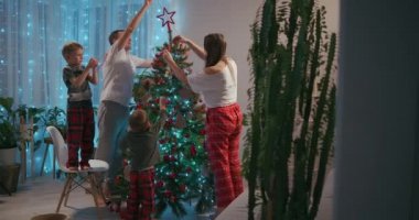 Mutlu aile yeni yıl kutlamaları için hazırlanıyor. Genç 30 'lu yaşlarda, anaokulundaki sevimli oğlu Noel ağacını süsleyen iki oğlu modern konforlu bir ortam yaratıyor.