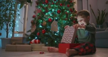  Mutlu Gülümseyen Küçük Çocuk Noel hediyesini Noel Baba 'dan açıyor. Çocuk Noel hediyesini evde açıyor..