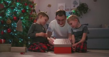 İki çocuklu baba ağacın altında bir Noel hediyesi açar ve sevinir. Babam için bir hediye. Hediyeden bir ışık ışığı yüzünde parlıyor. Çocukların yeni yıl hediyeleriyle sevinin..