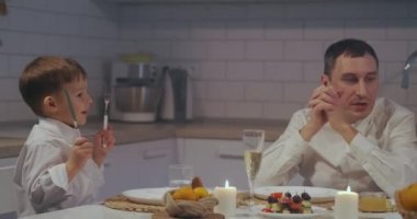 Çocuk tatilde bir pasta istiyor. 3-5 yaşlarında bir çocuk gülüyor ve tatil masasında pasta istiyor. Tebrik et ve yemek iste.