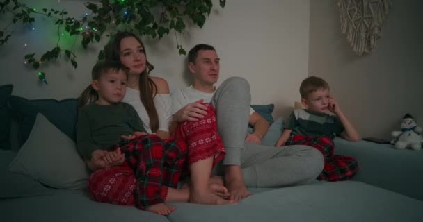 Kavkazská rodina sedí společně na pohovce a dívá se na televizi doma během vánočních svátků, zdobený bytový interiér — Stock video