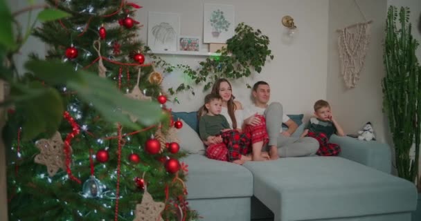 Rodzinna więź w święta. razem na kanapie i oglądanie telewizji w domu podczas świąt Bożego Narodzenia — Wideo stockowe