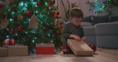 Sevimli üç yaşındaki çocuk Noel hediyesini açıyor ve içinde bir oyuncak ayı buluyor.