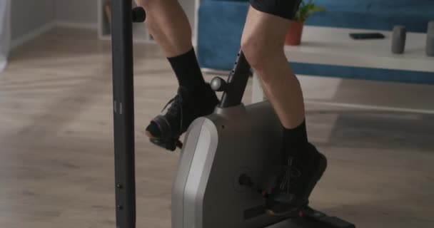 Entrenamiento en bicicleta estacionaria, los pies masculinos están girando pedales, vista de cerca, estilo de vida saludable, mantenerse en forma — Vídeo de stock