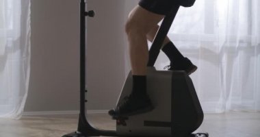 Spor salonunda ya da evde bisiklet çevirme eğitimi, büyük pencereli duvara yaslanmış orta yaşlı bir adamdan antrenman.
