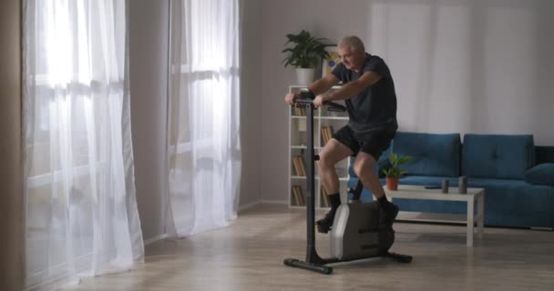 O homem de meia-idade está treinando no esforço na sala de estar, cuidando da saúde e perdendo peso, mantendo-se em forma — Vídeo de Stock