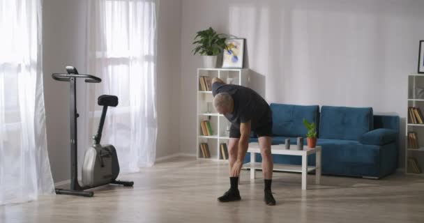 中年男性は週末の朝家で体操をしたり筋肉や関節を温めたり — ストック動画