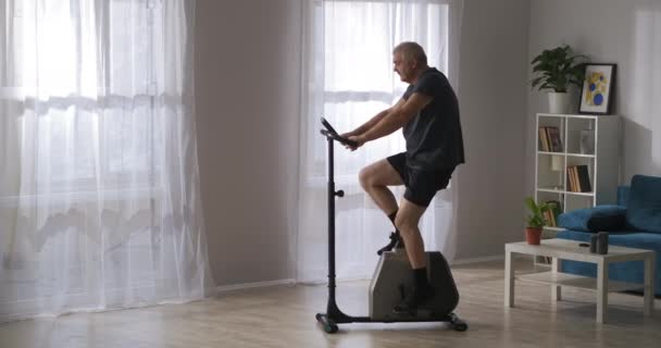 Otthoni edzés modern testmozgás kerékpár, fogyás és tartása fitt középkorú férfi — Stock videók
