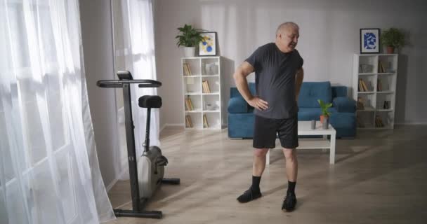 Gimnastyka dla zapobiegania osteochondrozie, mężczyzna w średnim wieku trenuje samotnie w niedzielę rano — Wideo stockowe
