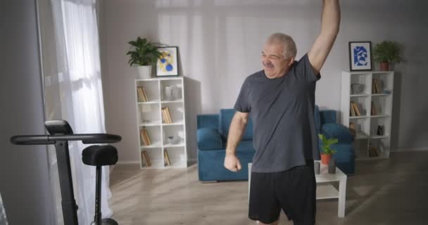 Man van middelbare leeftijd met vertebrale pijn doet gymnastiek thuis, genezing en preventie van spinale ziekten — Stockvideo