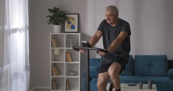 Oudere atleet traint thuis op hometrainer, portretfoto, lichamelijke conditie behouden — Stockvideo