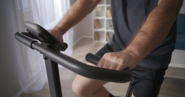 Orta yaşlı bir adam evde egzersiz bisikleti eğitimi alıyor, sağlıklı bir yaşam tarzı, fiziksel durumunu koruyor.