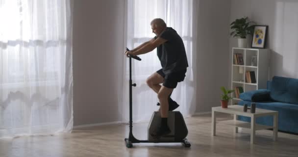 노인은 거실에서 자전거타기 훈련을 받고 있고, 상해를 입은 후 재활 훈련을 받고 있으며, 신체 건강을 유지하고 있다 — 비디오