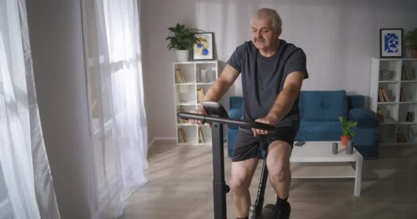 Homme d'âge moyen athlétique s'entraîne sur l'exercice dans le salon, mode de vie sain à la période d'isolement pendant la pandémie — Video