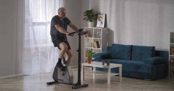 Allenamento in cyclette per perdere peso e mantenere la condizione fisica, uomo di mezza età a casa — Video Stock