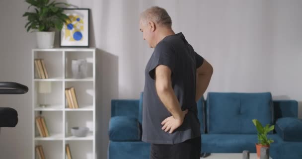 Muž středního věku provádí sportovní aktivitu doma, prevenci osteochondrózy ve středním věku — Stock video