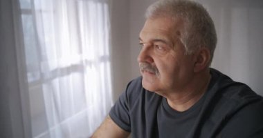 Evinin oturma odasında bisiklete binen orta yaşlı bir adamın portresi, izolasyon döneminde evde eğitim.