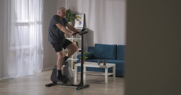 가정에서의 정지 자전거 훈련, 중년기의 스포츠 활동, 인간은 회전하는 페달, 호흡 훈련을 하고 있다 — 비디오