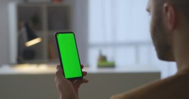 Krom anahtar teknolojisi için yeşil ekranlı modern akıllı telefonu elinde tutan adam, sosyal ağlarda video izliyor.