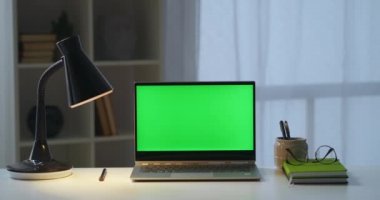 Adam masadaki yeşil ekranlı dizüstü bilgisayarın kapağını kapatıyor. Serbest ofis, yazar ya da apartmandaki serbest çalışan kişi.