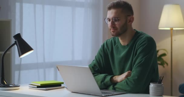 Online communicatie via video chat, jongeman gekleed groene sweater en bril is op zoek naar weergave van notebook en knikken hoofd — Stockvideo