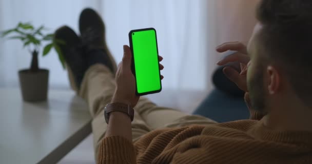 Hombre está llamando por chat de vídeo en el teléfono inteligente desde casa u oficina en el momento del descanso, pantalla verde en el gadget — Vídeos de Stock