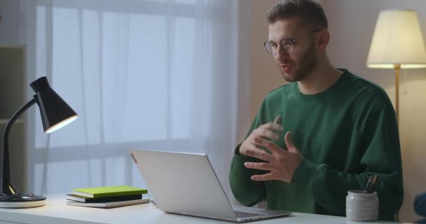 Dospělý muž zdraví kolegy a partnery na online setkání, mluví a mává rukou na webkameru, pracuje z domova — Stock video