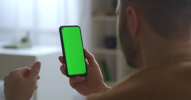 Зв'язок за допомогою програми в смартфоні, відео виклик на зеленому екрані, чоловік говорить і дивиться на дисплей, крупним планом — стокове відео
