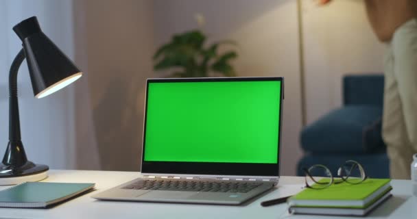 Mann schaltet Stehlampe in Wohnung aus und schließt Laptop mit Chroma-Schlüsselanzeige auf Tisch im Zimmer, Home Office von Freelancer — Stockvideo