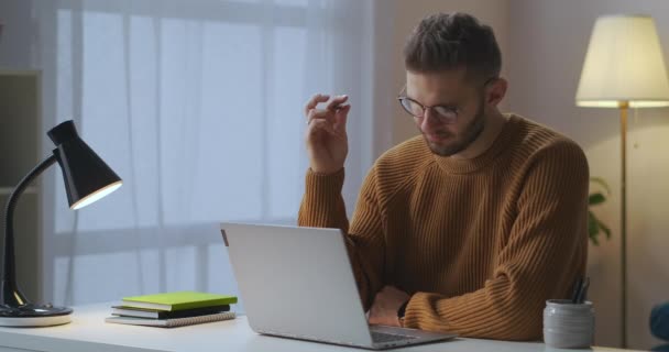 Bedachtzame man zit voor laptop in kamer en denken, spinnen pen in de hand, schrijver of journalist — Stockvideo