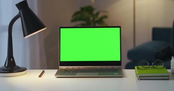 Arbetsplats för författare eller frilansare i lägenhet, bärbar dator med grön skärm för kromnyckel, böcker och lampa på bordet — Stockvideo
