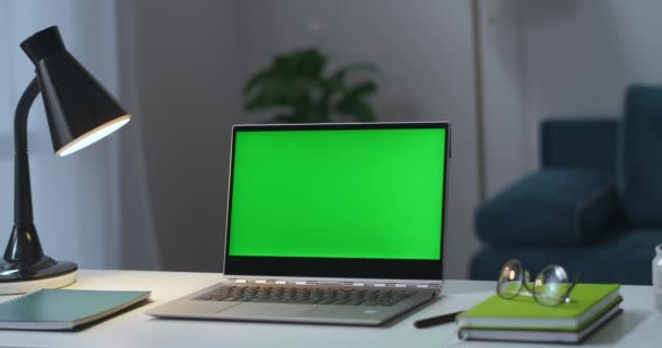 Τραπέζι εργασίας στο σπίτι, φορητό υπολογιστή με χρωματική οθόνη κλειδί, λάμπα, γυαλιά και βιβλία, ο άνθρωπος ανάβει λάμπα δαπέδου — Αρχείο Βίντεο