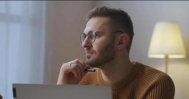 Człowiek pracuje nad projektem w domu, wolnym strzelcem i pracą na pół etatu, siedzi przed notebookiem w pokoju — Wideo stockowe