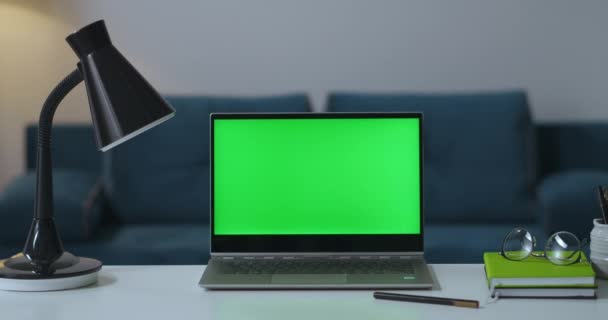 Miejsce pracy w salonie, stół wolnego strzelca z laptopem, lampa, książka i okulary, zielony ekran dla technologii chroma key — Wideo stockowe