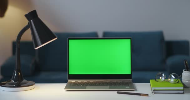 사람들은 저녁에 전등과 노트북을 켜고 작업을 마치고 크로마 키 기술을 위한 노트북의 녹색 화면을 켜고 있습니다. — 비디오
