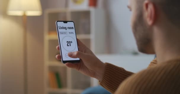 Smart-Home-Technologie: Der Mensch steuert per Smartphone-Anwendung die Temperatur in den Räumen — Stockvideo