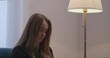Uzun saçlı güzel bir kadın apartman dairesinde dinleniyor. Lambanın ışıklarını kapatıyor.