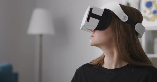 Usuário feminino está testando novo modelo de exibição montada na cabeça para a realidade virtual, retrato médio da mulher dentro de casa, gadget para jogos de vídeo — Vídeo de Stock