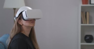 Evde VR kulaklık kullanan genç bir kadının portresi, oyun ve eğitim için HMD ekranı