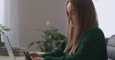 Yetişkin bir kadın hafta sonu evde dizüstü bilgisayarla çalışıyor. Mesaj göndermek için internet bağlantısı olan bir laptop kullanıyor.