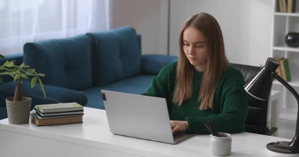 Young woman is working with laptop in living room, surfing internet by modern notebook, using social nets — Stock Video