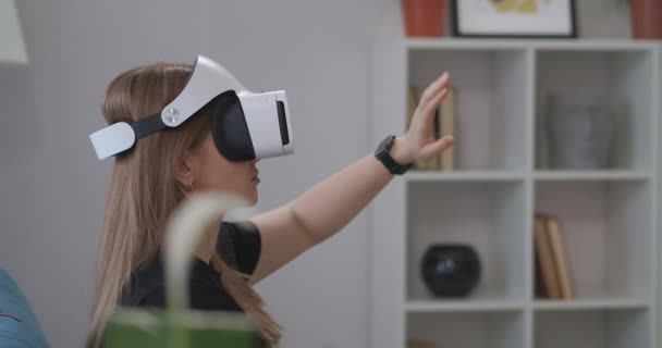 HMD ekran kullanan etkileşimli eğitim programı, kadın evde VR kulaklık takıyor, elleriyle hareket ediyor — Stok video