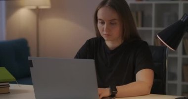 Bayan öğrenci akşam evde dizüstü bilgisayarla çalışıyor, ödev yapıyor, online çalışıyor, seminere hazırlanıyor.