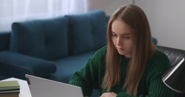 Jonge vrouw werkt op afstand van huis, met behulp van laptop in de woonkamer, freelancer en onafhankelijke specialist — Stockvideo