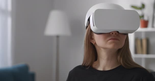 Mujer está viendo la realidad virtual por la pantalla moderna montada en la cabeza en la sala de estar, retrato medio de usuario femenino en el interior — Vídeos de Stock