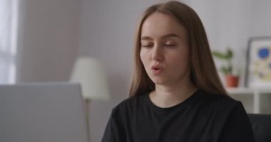 Kadın, meslektaşları ve ortaklarıyla yaptığı uzak görüşmede internet üzerinden görüntülü konuşma yaparak webcam ve laptop ekranına bakıyor.